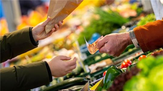 An einem Marktstand wird mit Bargeld eingekauft: Höhere Teuerungsraten schmälern die Kaufkraft von Verbrauchern.