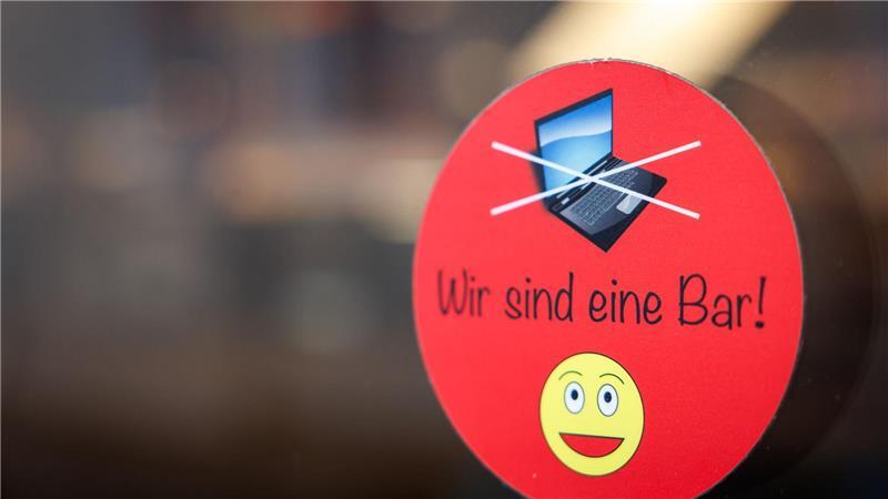 An einer Scheibe der Café-Bar 8tto Grammi in Bayreuth weist ein Schild auf das Verbot von Laptops hin.