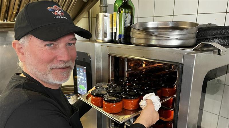 Erfolgsgeschichte aus Buxtehude: Chili Jungs erobern die Supermärkte André Grote schiebt ein Tablett mit frisch eingefüllter Salsa in den Einkochautomaten.