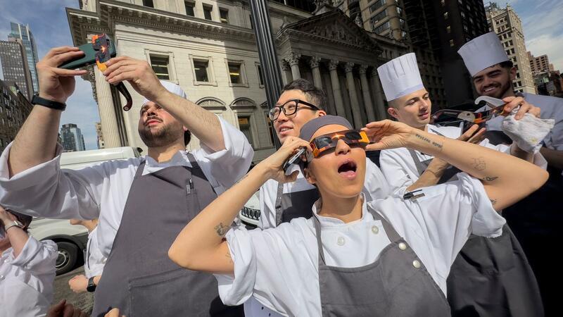 Millionen Menschen sehen totale Sonnenfinsternis Angestellte eines Restaurants in Manhattan machen eine Pause, um die Sonnenfinsternis zu betrachten.