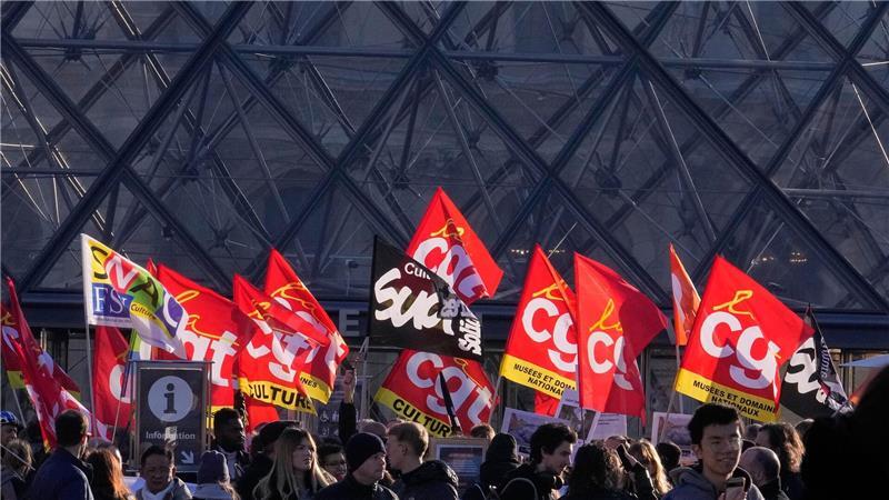 Angestellte zeigen Fahnen der Gewerkschaft CGT vor dem Louvre.