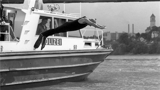 Angetan mit einer Badekappe, einem Schutzanzug und Schwimmflossen, springt Klaus Töpfer (CDU), damaliger Bundesumweltminister, von Bord eines Polizeibootes in den Rhein. Der damalige Bundesumweltminister wollte mit seinem spektakulären Sprung beweisen, dass nach einer Reihe von Chemikalieneinleitungen die Flüsse wieder regenerierten.