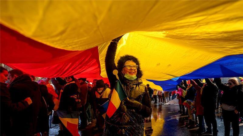 Anhänger von Georgescu, dem Gewinner der ersten Runde der rumänischen Präsidentschaftswahlen, die vom Verfassungsgericht für ungültig erklärt wurde, stehen unter einer rumänischen Fahne während einer Demonstration.