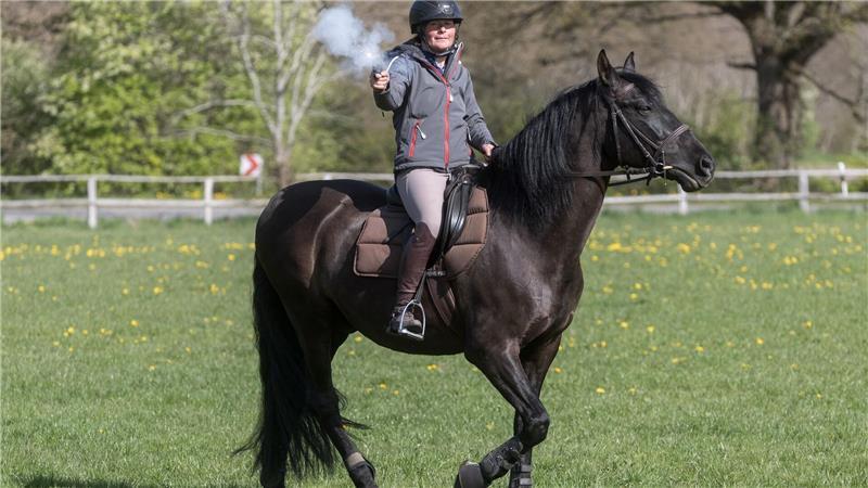 Anna Weiler feuert auf dem Rappen Oro, der bei den Karl-May-Spielen Winnetous Pferd Iltschi darstellt, einen Schreckschuss-Revolver ab.