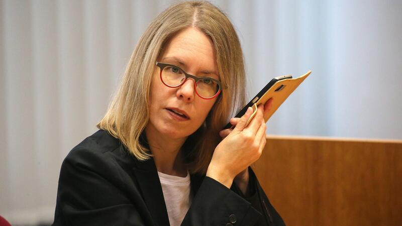 Anne Brorhilker, Oberstaatsanwältin, hört am Rande eines Prozesses um Cum-Ex-Deals im Landgericht in ihr Smartphone.