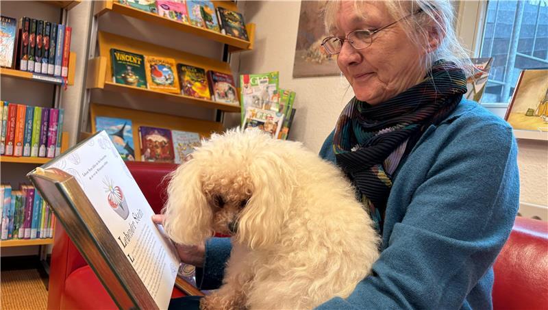 Annette Kokott und Büchereihündin Maudi in der Leseecke der Kinderabteilung.