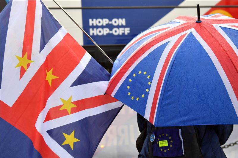 Anti-Brexit-Demonstranten stehen vor dem Parlament mit einer Fahne und einem Schirm, gestaltet mit EU-Symbolen auf der britischen Fahne. Foto: Dominic Lipinski/PA Wire/dpa
