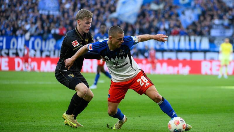 Anton Kade (FC Augsburg, l-r) und Miro Muheim (Hamburger SV) kämpfen im Mittfeld um den Ball.