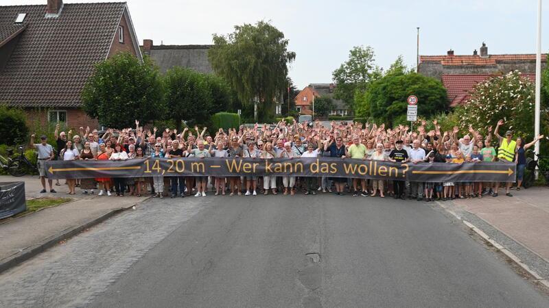 Anwohner gehen auf die Barrikaden: Symbolisch spannen sie in Steinkirchen in der Bürgerei einen Banner „14,20 Meter - Wer kann das wollen?“ über die Straße, laut Bürgermeisterin Sonja Zinke (CDU) wird die Straße inklusive Fußweg an dieser Stelle 13,80 Meter breit.