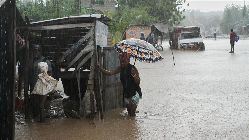Anwohner waten durch eine überflutete Straße nach dem durchzug von Hurrikan Melissa in Petit-Goave.