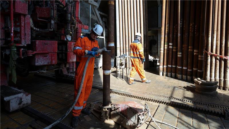 Arbeiter montieren im Bohrturm einen neuen Bohrstrang.