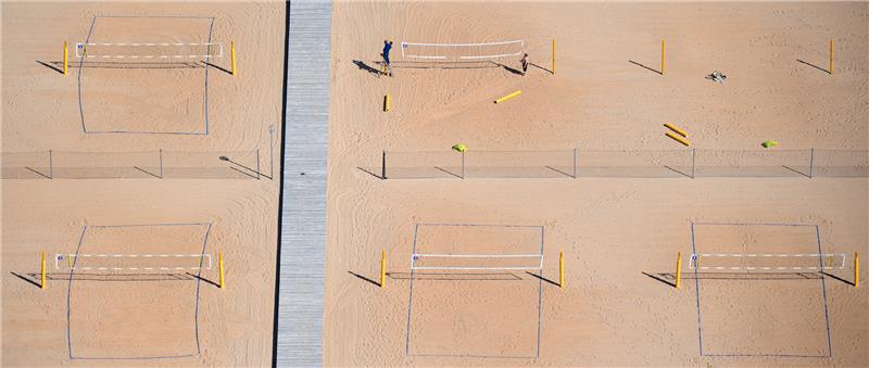 Arbeiter nutzen das schöne Wetter und bauen auf einer Sportanlage in Bayern Beachvolleyballfelder auf. Foto: Sven Hoppe/dpa