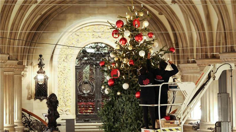 Arbeiter schmücken den Weihnachtsbaum in der Rathausdiele.