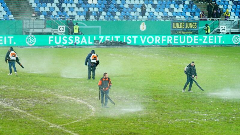 Nach Absage in Saarbrücken: Wie geht es im DFB-Pokal weiter? Arbeiter versuchten, Wasserlachen vom Spielfeld im Ludwigsparkstadion zu entfernen.
