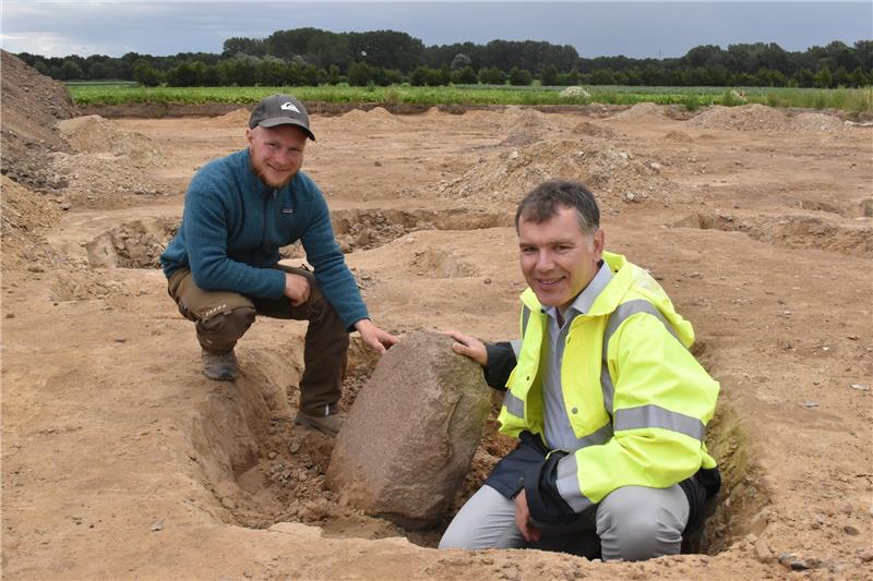 Archäologe Sebastian Düvel von der Grabungsfirma „ArchaeoFirm“ und Kreisarchäologe Daniel Nösler von der Archäologischen Denkmalpflege (von links) präsentieren ein 2500 Jahre altes „Küchengerät“ – entdeckt bei der Ausgrabung einer eisenzeitlichen Siedlung im Zuge der Erschließung des Baugebiets „An der Blide“ in Beckdorf. Es ist ein Mahlstein. Fotos: Vasel