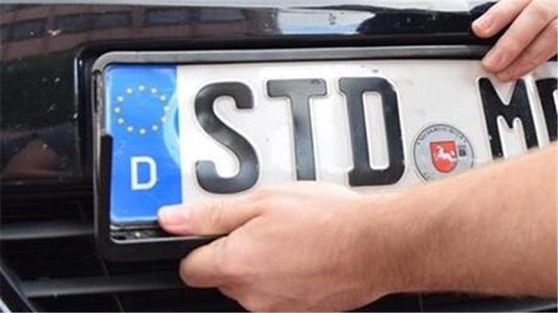 Ein Mann montiert ein STD-Kennzeichen an einem Auto.