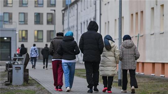 Asylsuchende gehen über das Gelände der Zentralen Erstaufnahmeeinrichtung für Asylbewerber des Landes Brandenburg in Eisenhüttenstadt.