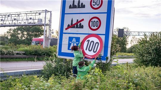 Auf Autobahnen gilt ... ein Tempo-100-Tempolimit? So zumindest wollen es Greenpeace-Aktivistinnen, hier bei der Aktion am Montagmorgen in Aachen. 