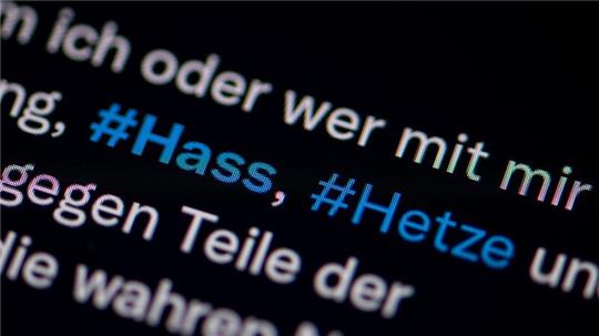 Auf dem Bildschirm eines Smartphones sieht man die Hashtags Hass und Hetze in einem Twitter-Post.