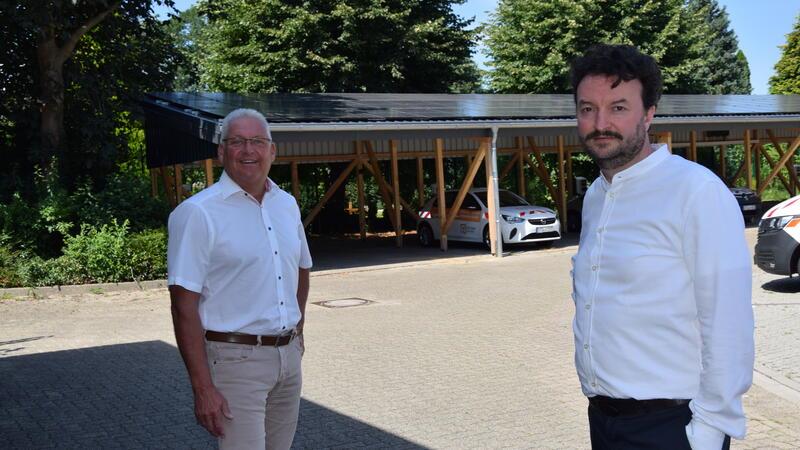 Auf dem Dach des Carports der Stadtwerke Buxtehude erzeugen Solarmodule Strom. Geschäftsführer Stefan Babis (links) und der kaufmännische Prokurist Daniel Berheide stehen vor der Photovoltaikanlage. 