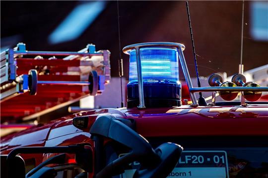Auf dem Dach eines Einsatzfahrzeugs der Feuerwehr leuchtet ein Blaulicht.