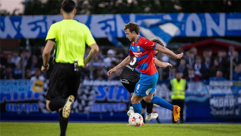 Auf dem Platz setzt D/A-Mittelfeldspieler Matti Steinmann Akzente. Im Gästeblock können sich einige der 400 mitgereisten Meppen-Fans offensichtlich nicht benehmen.