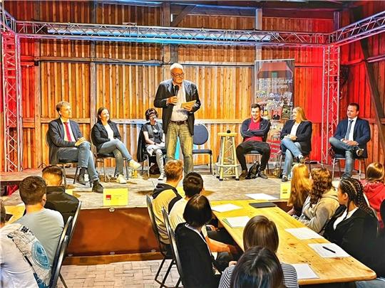 Auf dem Podium in der Kulturscheune Drochtersen (von links) bühnenwirksam ausgeleuchtet: Marlon Borchers (Linke), Corinna Lange (SPD), Sandra Deutschbein (Grüne), Moderator Thomas Rosteck, Kilian Würsig (FDP), Melanie Rost-Reinecke und Seba