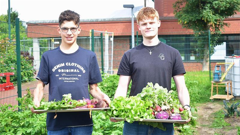 Auf dem Silbertablett serviert: Amatus (links) und Kevin präsentieren die Ernte-Ausbeute vom Gemüseacker der Geestlandschule. Für beide ist es der Beginn eines besonderen Tages.