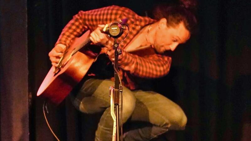 Mense springt mit seiner Gitarre in die Luft