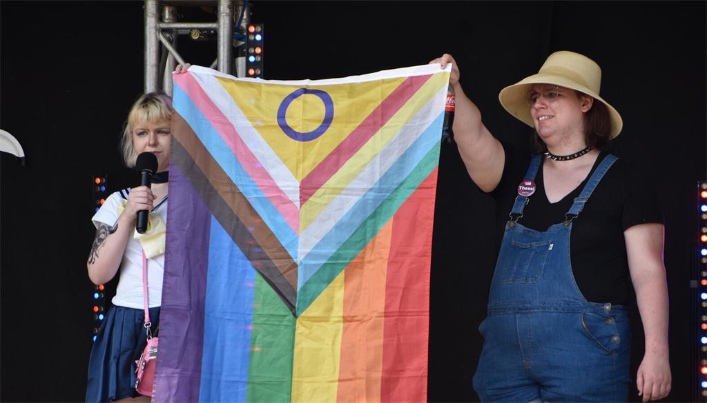 Auf der Bühne wird die erweiterte Version der Pride-Flagge präsentiert. 