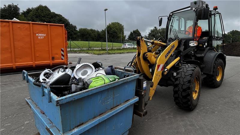 Auf der Gabel des kleinen Komatsu-Radladers befördert Rainer Schuran einen Elektroschrottcontainer zum großen Sammelcontainer.