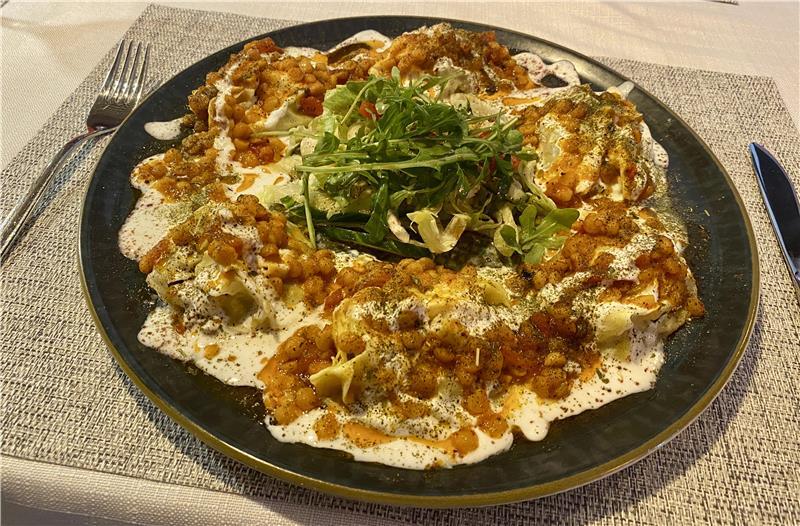 Auf einem Tisch steht ein Teller mit dem afghanischen Gericht Mantu.