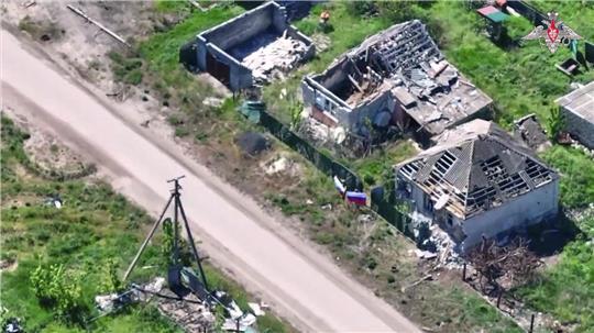 Auf diesem Standbild aus einem vom Pressedienst des russischen Verteidigungsministeriums via AP verbreiteten Video halten zwei russische Soldaten russische Nationalflaggen in einer Straße, nachdem das Dorf Torske in der Region Donezk in der Ukraine unter die Kontrolle der russischen Armee geraten ist.