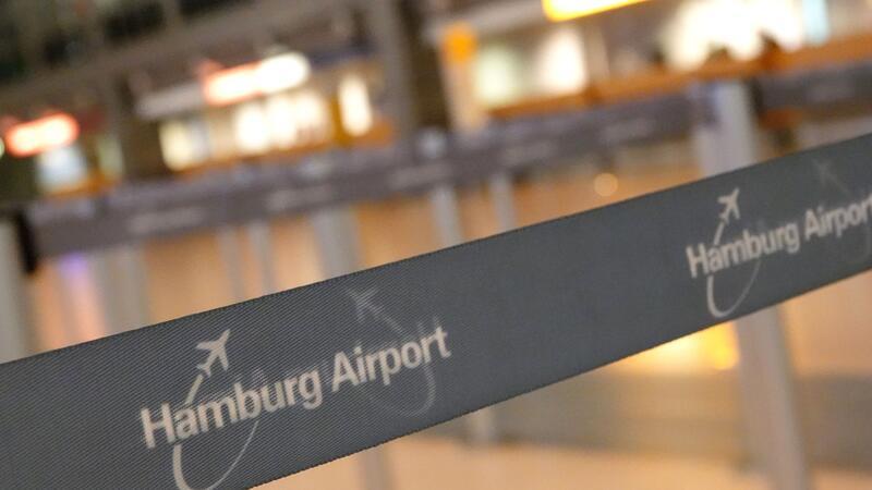 Auf einem Absperrband im Terminal 2 steht der Schriftzug „Hamburg Airport“, im Hintergrund befindet sich ein Serviceschalter der Lufthansa.