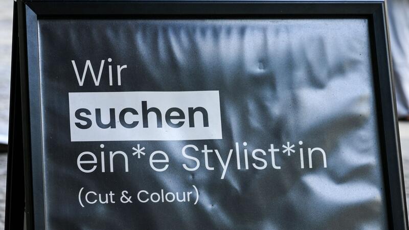Auf einem Schild wird gendergerecht eine Stylistin beziehungsweise ein Stylist gesucht.