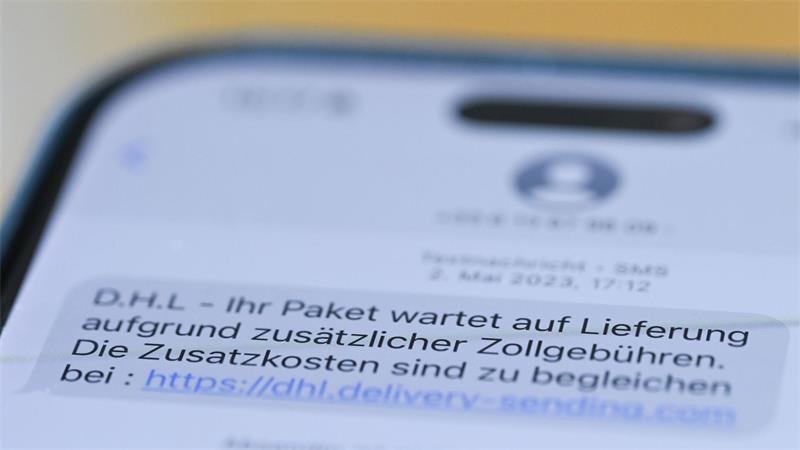 Auf einem Smartphone ist eine Betrugs-SMS zu lesen, in der Kriminelle ein Paket ankündigen und dafür angeblich fällige Zollgebühren einfordern.
