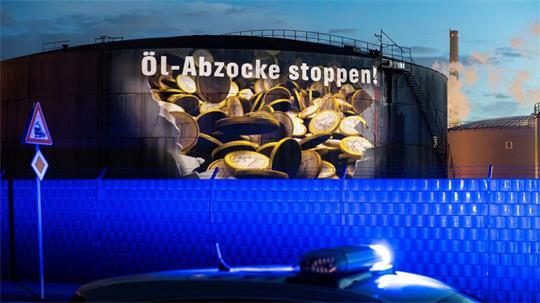 Auf einem Tank einer Raffinerie im Hamburger Hafen wird am frühen Morgen Geldregen projiziert.