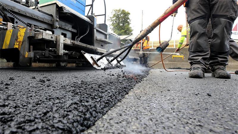 Auf einem Teilstück der Straße Ostfeld in Jork wird die Asphaltdeckschicht erneuert. (Symbolbild)