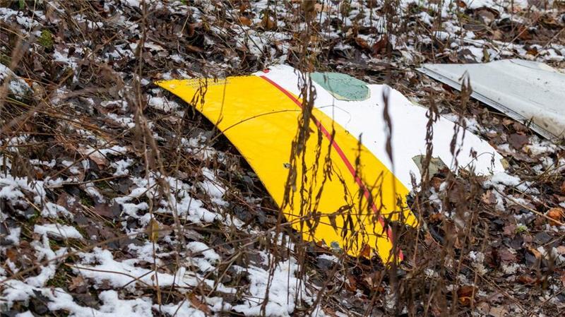 Auf einem Trümmerteil des abgestürzten Flugzeugs sind die DHL-Farben zu sehen.