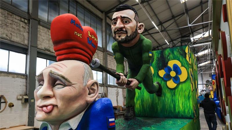 Trump, Musk und Putin im Kölner Rosenmontagszug Auf einem der Wagen versucht der ukrainische Präsident Wolodymyr Selenskyj, dem russischen Präsidenten Wladimir Putin die Botschaft „Make Love not War“ einzuhämmern.