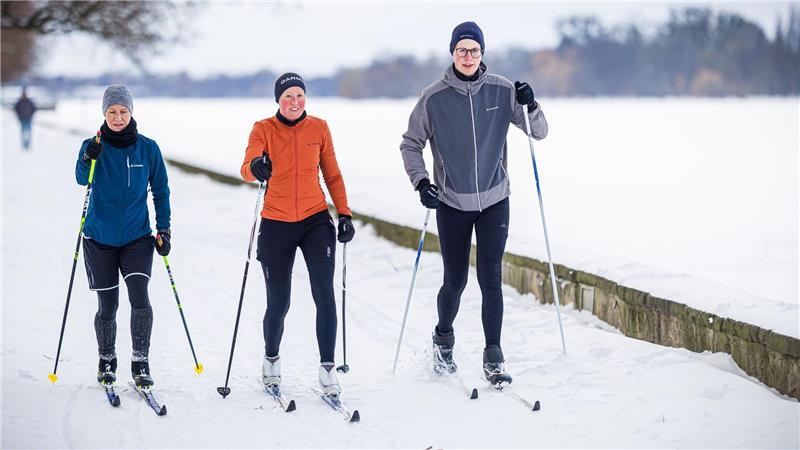 Auf einem verschneiten Weg am Maschsee in Hannover sind drei Langläufer unterwegs.