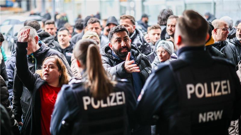 Aufgebrachte Kunden diskutieren vor der Sparkassenfiliale in Buer mit Polizeibeamten nach der Räumung des Vorraums der Filiale.