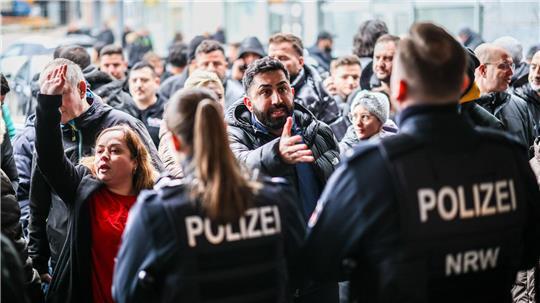 Aufgebrachte Kunden diskutieren vor der Sparkassenfiliale in Buer mit Polizeibeamten nach der Räumung des Vorraums der Filiale.