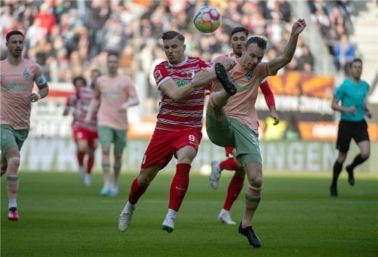 Augsburgs Emirdan Demirovic (links) und Bremens Christian Groß kämpfen um den Ball. Foto: Stefan Puchner/dpa