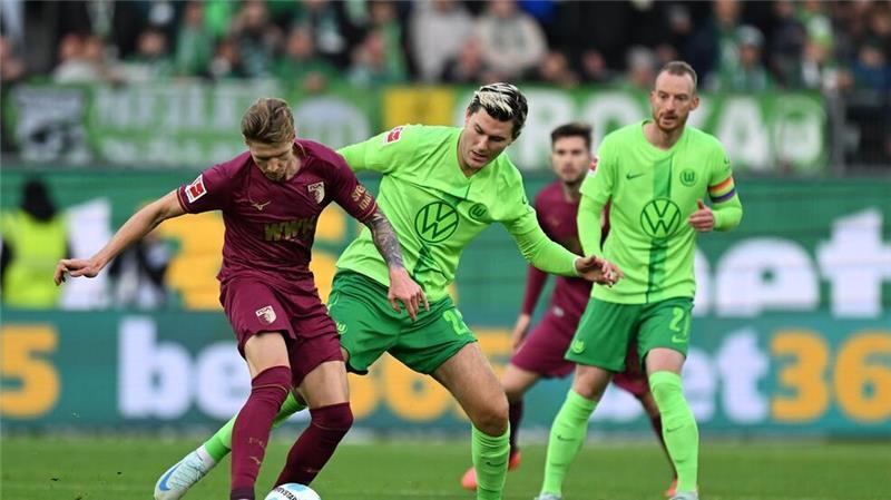 Augsburgs Kristijan Jakic (l) spielt gegen Wolfsburgs Jonas Wind.