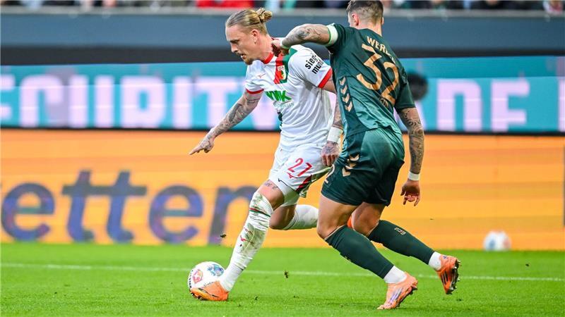 Augsburgs Marius Wolf (l) im Zweikampf mit Werder-Verteidiger Marco Friedl. 