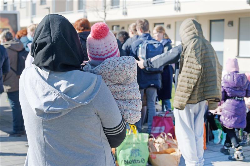 Aus der Ukraine vertriebene Menschen stehen mit ihrem Gepäck vor einem Flüchtlingsheim.