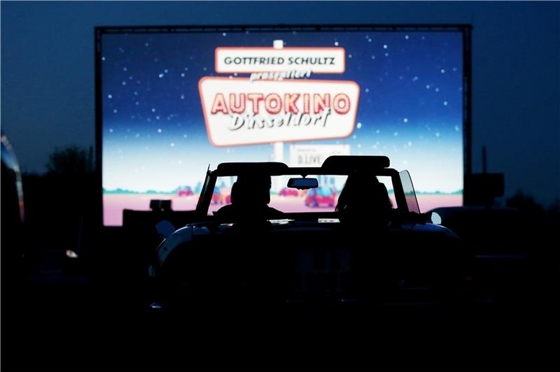 Aus einem Cabrio schauen zwei Besucher bei einer Probevorführung auf die Leinwand des Autokinos . Foto: Young/dpa