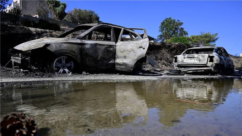 Bilder des Tages Ausgebrannte Autos spiegeln sich im Wasser nach einem Waldbrand in dem Dorf südöstlich von Athen.
