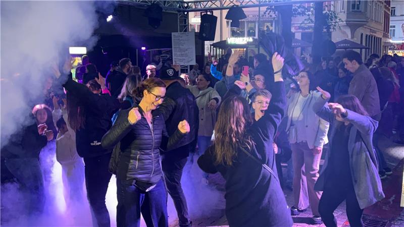 Ausgelassen tanzen die Gäste der Open-Air-Disco am Geesttor zu elektronischen Beats. Die Tanzfläche ist in Bühnennebel gehüllt.